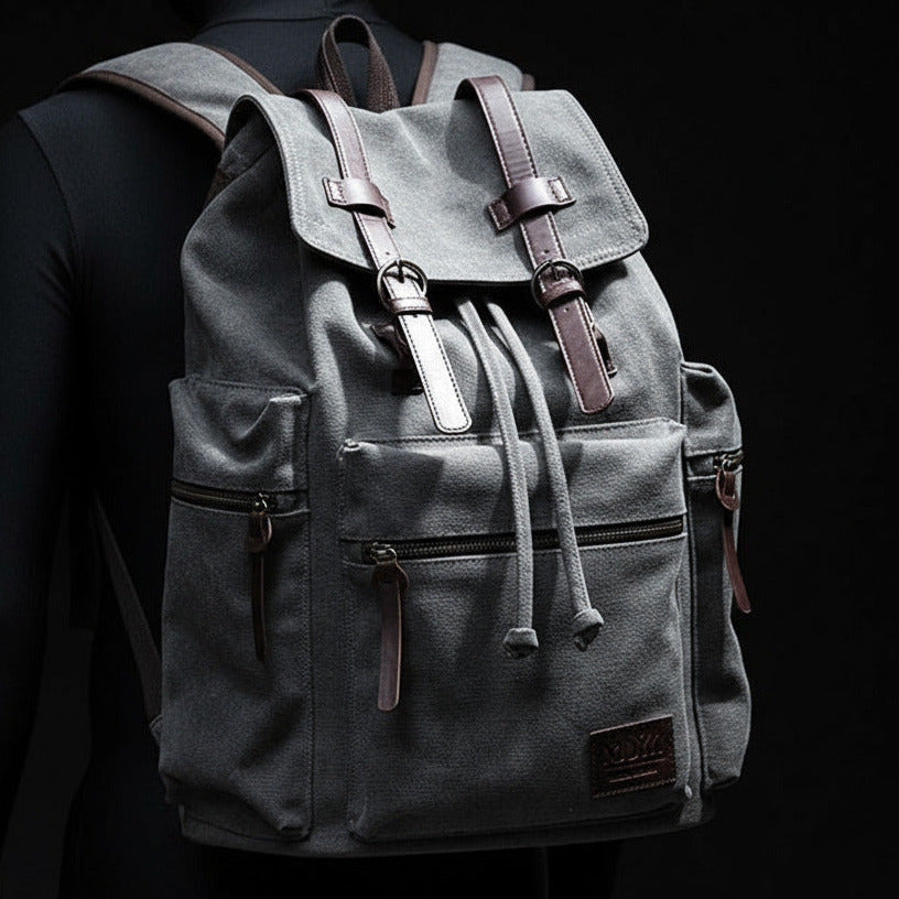 Person wearing a gray backpack with leather straps against a black background