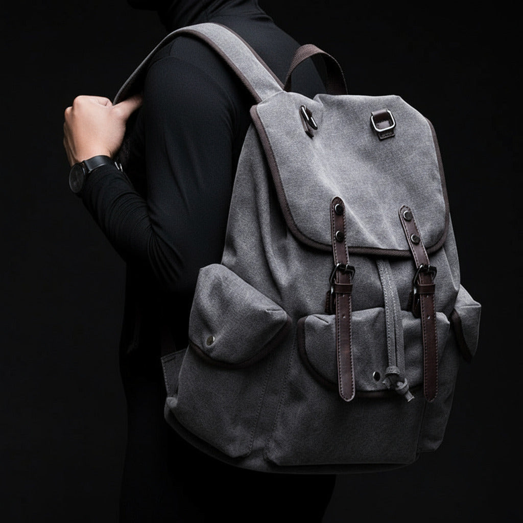 Person wearing a gray backpack with brown straps against a blurred background