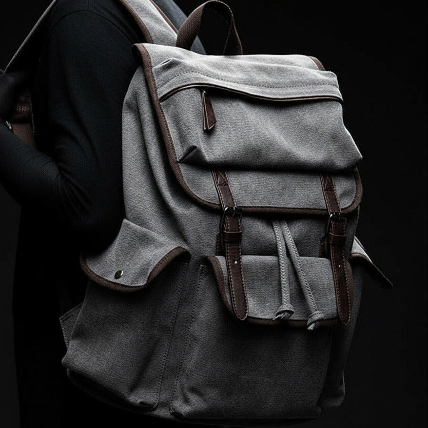 Person wearing a gray backpack with brown straps against a blurred background
