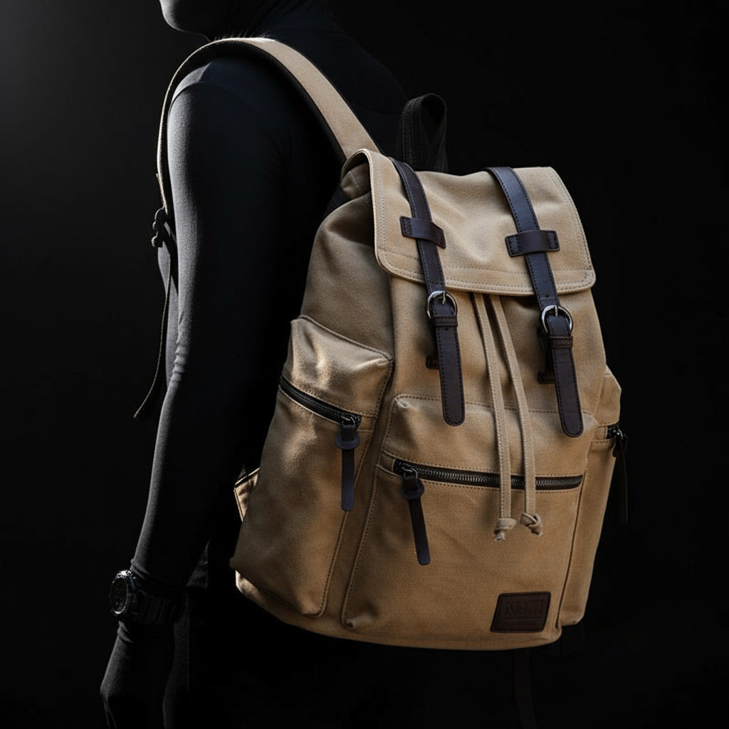 Beige backpack with leather straps worn by a person in a black room