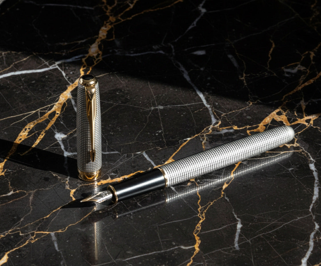 Fountain pen with detailed design on a black and gold marble background