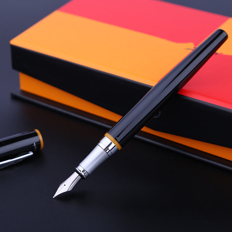 Fountain pen with a black and silver design on a dark surface with an orange and red book in the background.